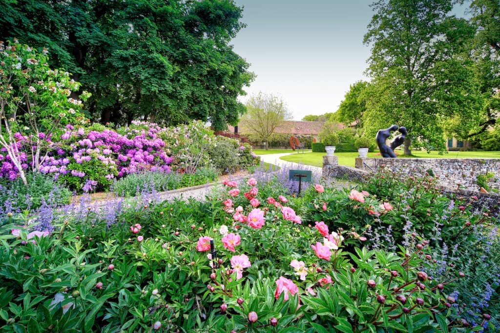 Plan large du jardin de Daria du Château de Vullierens avec des rhododendrons et de pivoines en fleurs.