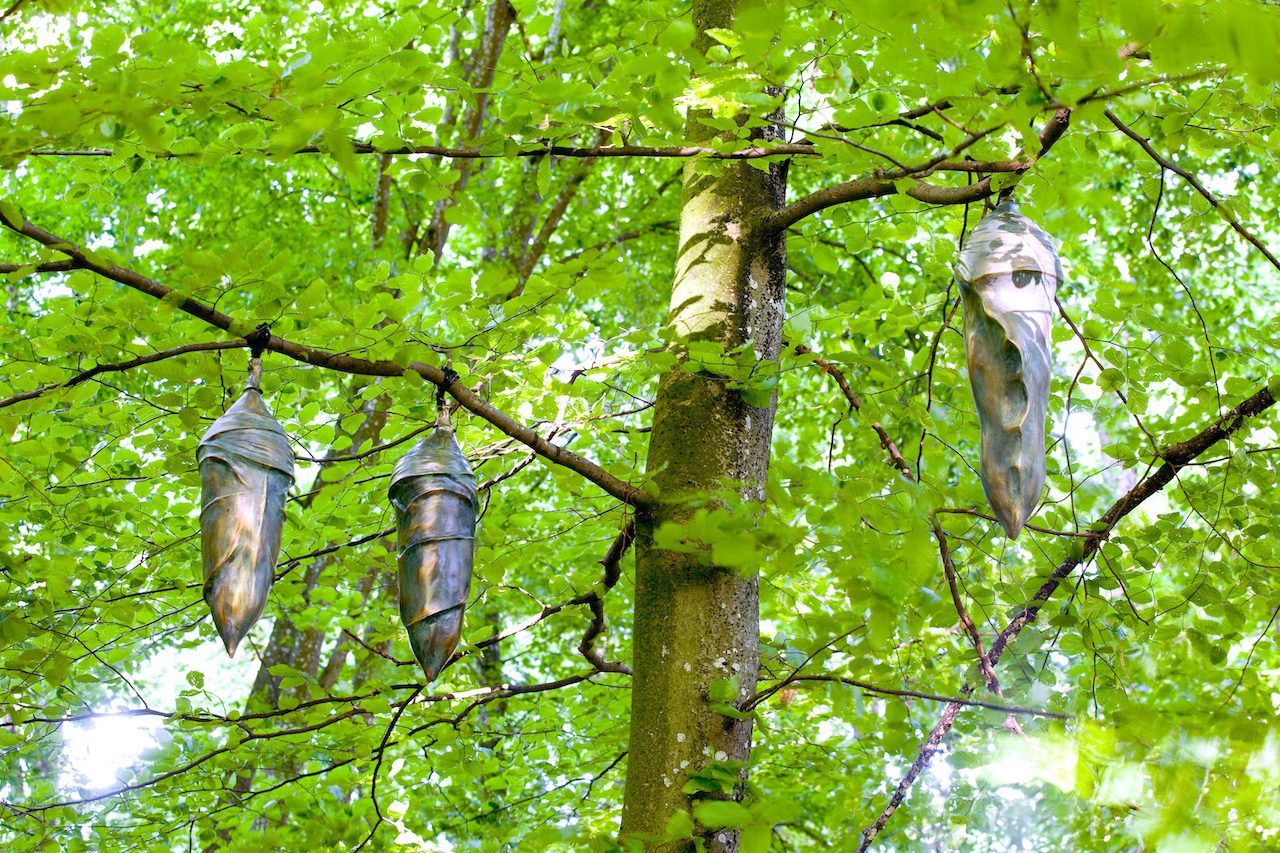 Statues de Sara H suspendue aux branches d'arbres dans la forêt du Château de Vullierens.