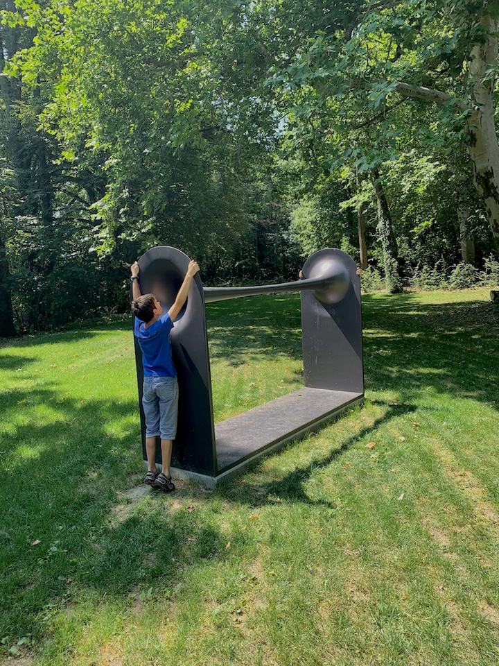 2 enfants sont en train de tester l'oeuvre Dià de Michele Spanghero, en se parlant à travers le petit trou.