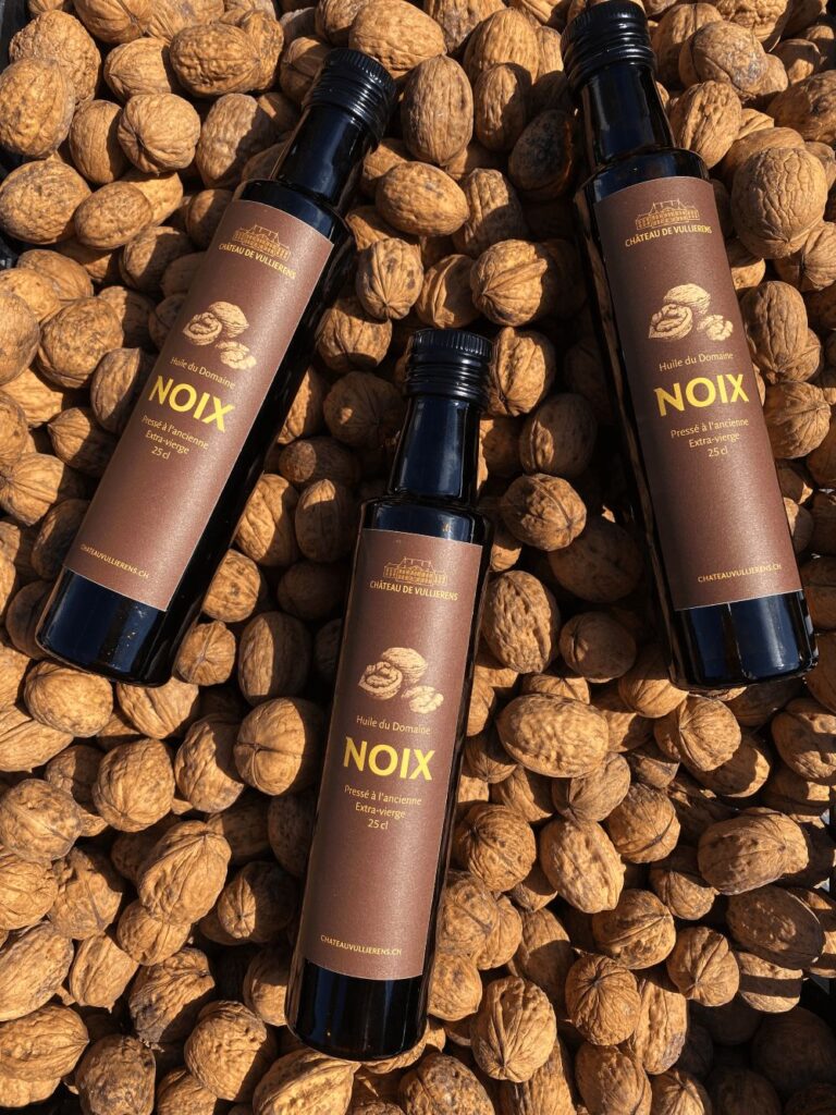 3 bouteilles d'huile de noix du domaine posées sur des noix en coquille.