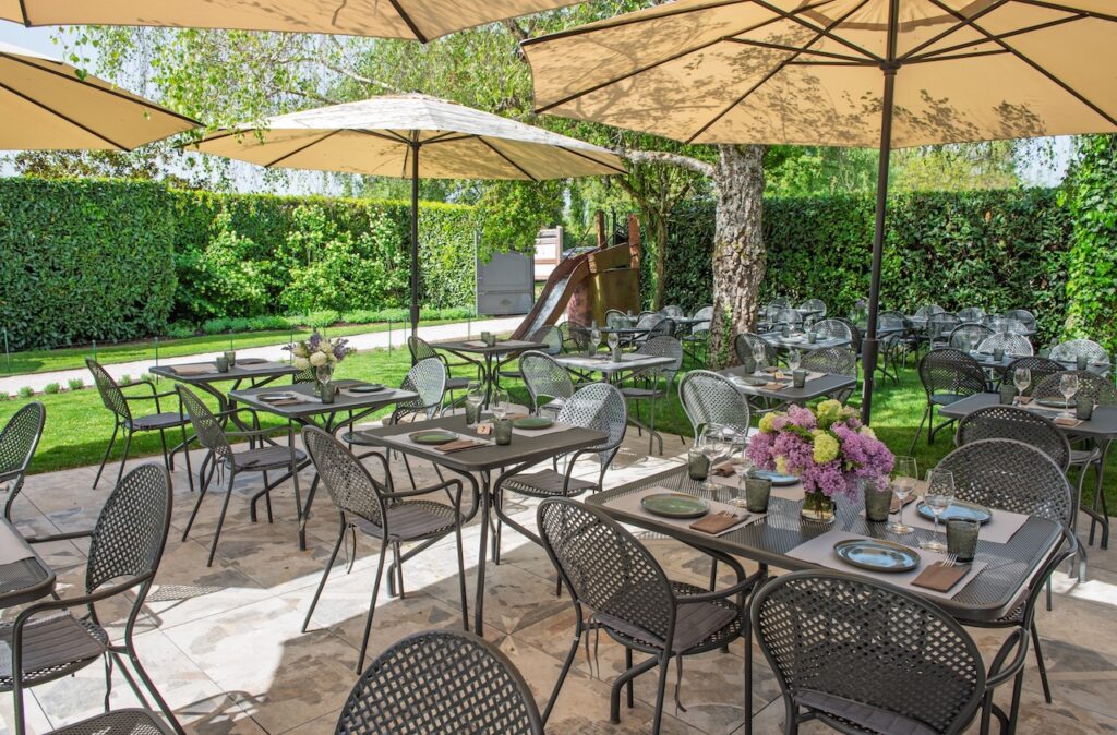Plan large de la terrasse du Café des Jardins, sans client, avec les tables dressées et parasols ouverts.