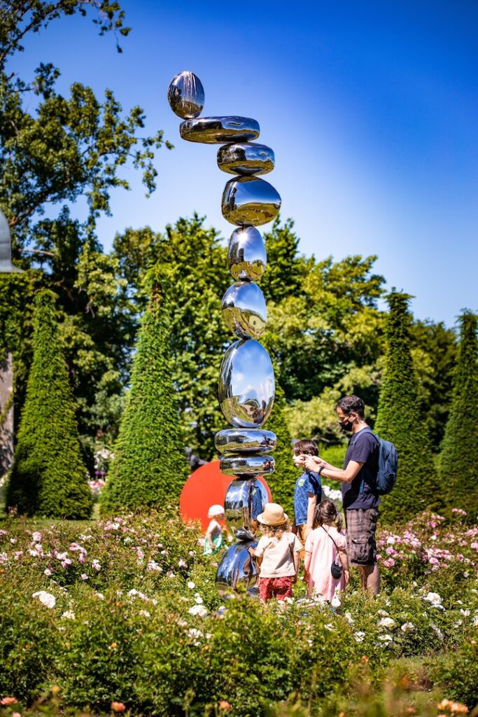 Un père et ses trois enfants en train de découvrir la sculpture Stones de Pol Quadens dans le jardin de Dorianne au Château de Vullierens.