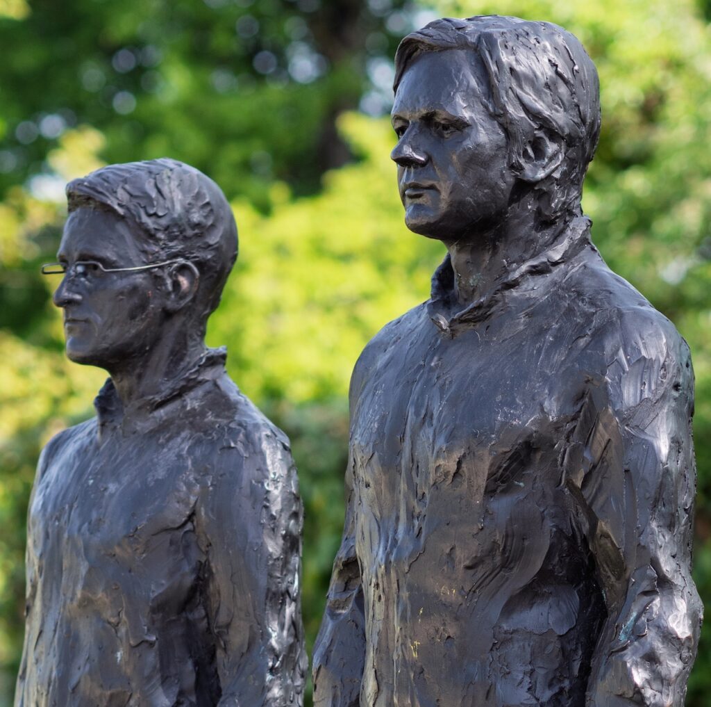 Close-up de l'oeuvre de Davide Dormino, représentant deux hommes en train de protester. Leur matière est de couleur noir.